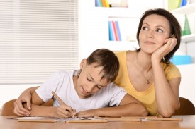 An image of a child doing homework while a parent looks on.