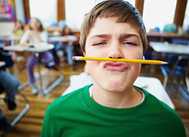 Image of a little boy with a pencil clenched between his nose and mouth.