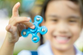 An image of a smiling child holding a fidget spinner.
