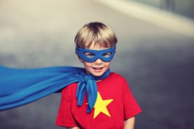 An image of a little boy in a superhero mask and a cape.