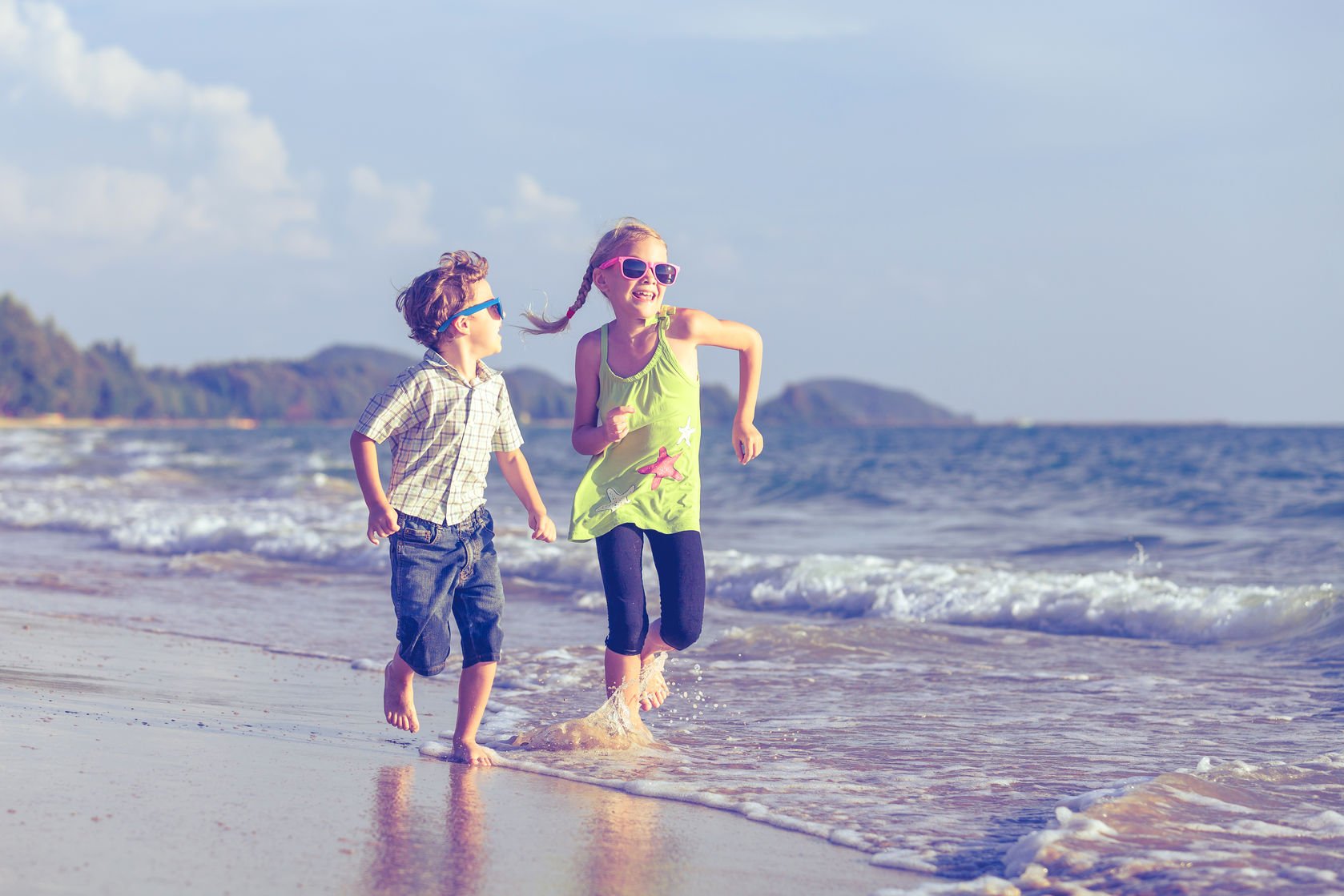 An image of children laughing and playing on a beach.