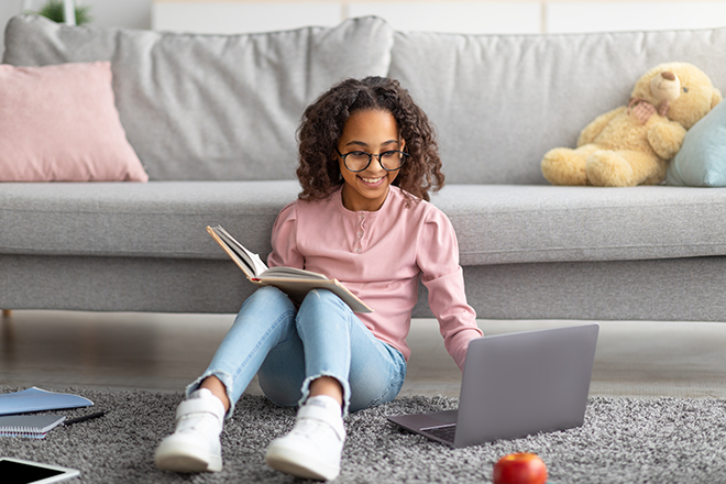 girl at home studying on laptop and reading book to overcome learning loss with science of reading