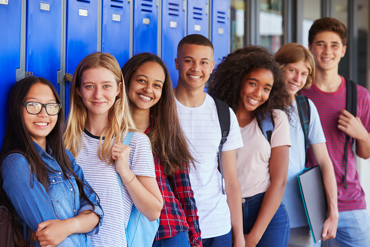 group of teens standing in front of blue lockers