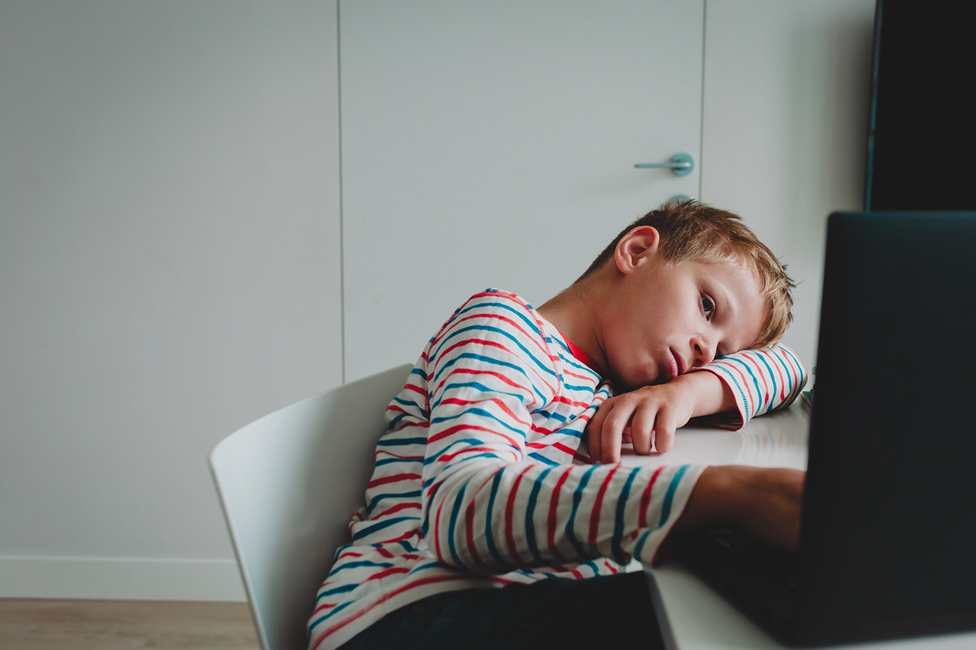 kid bored in front of laptop during remote learning